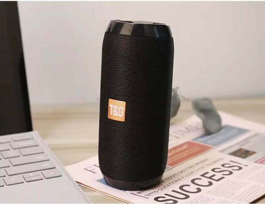 Waterproof portable Bluetooth-compatible speaker with AUX, FM radio, and loud sound on a desk.